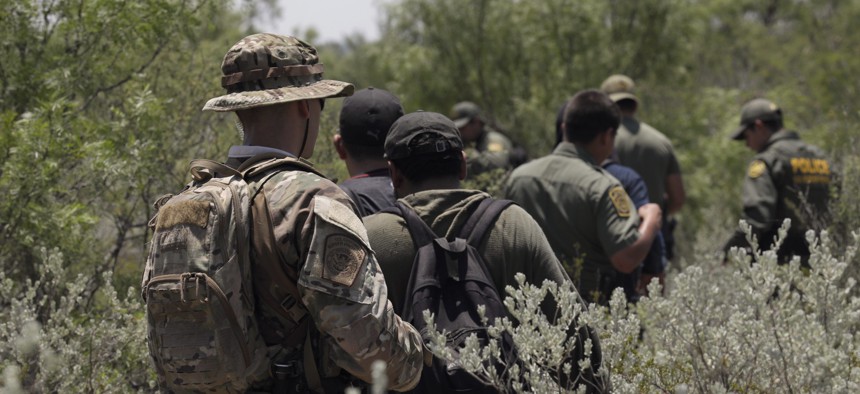  Four migrants are apprehended in dense brush by members of the U.S. Border Patrol Search, Trauma, and Rescue (BORSTAR) team are led to awaiting vehicles near Eagle Pass in June.