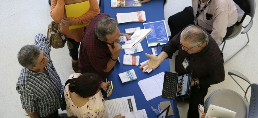 Alex Pereira, of the U.S. Census Bureau, right, talks with job applicants about temporary positions available with the 2020 Census, during a job fair designed for people fifty years or older on Sept. 18 in Miami. 