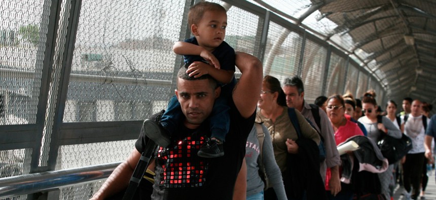 Cuban migrants are escorted by Mexican immigration officials in Ciudad Juarez, Mexico, as they cross the Paso del Norte International bridge to be processed as asylum seekers on the U.S. side of the border.