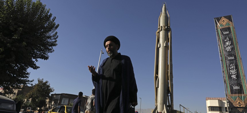A Muslim cleric walks in downtown Tehran, where a Shahab-3 surface-to-surface missile is on display on Sept. 25, 2019. 