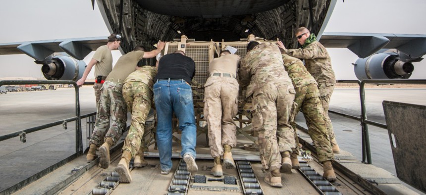 Soldiers, Marines, Airmen and civilian contractors push equipment into the cargo bay of a C-17 Globemaster III, assigned to the 816th Expeditionary Airlift Squadron, at Al Asad Air Base, Iraq Jan. 25, 2018. 