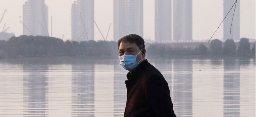 A man wears a face mask as he stands along the waterfront in Wuhan in central China's Hubei Province, which is at the center of the Coronavirus outbreak. 