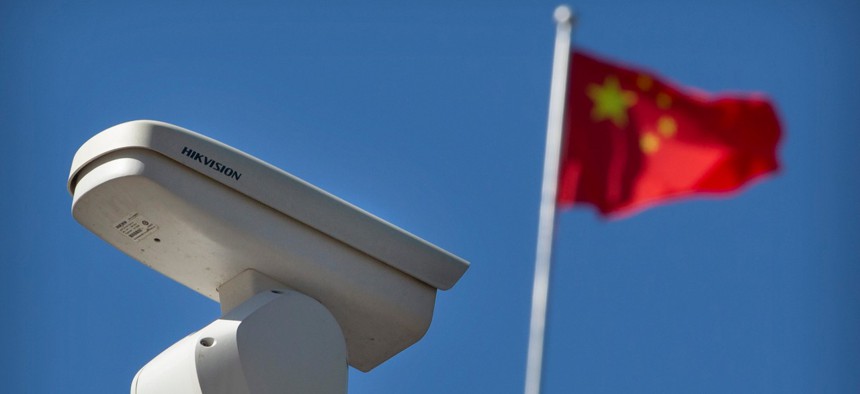 A Chinese flag flies near a Hikvision security camera monitoring a traffic intersection in Beijing, Tuesday, Oct. 8, 2019