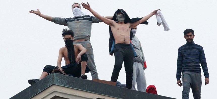 Inmates stand on the roof of the San Vittore prison to protest after restrictions that were imposed on family visits to prevent coronavirus transmissions in Milan, Italy, on Monday. The Federal Bureau of Prisons says it is prepared for the coronavirus. 