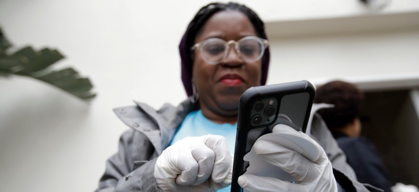 Millie Phaeton wears gloves as she checks her cell phone while volunteering at a food distribution center set up by the Dream Center on Monday in Los Angeles.