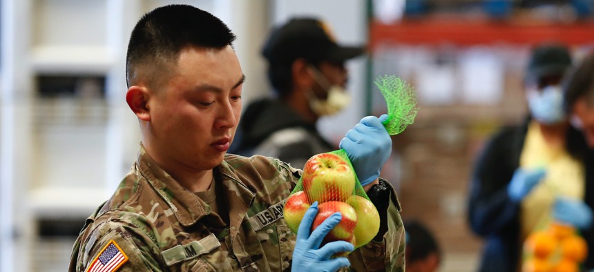 Sgt. Caleb Lim, of the California National Guard ties up a bag of apples at the Sacramento Food Bank and Family Services in Sacramento, Calif., Saturday, March 21, 2020.