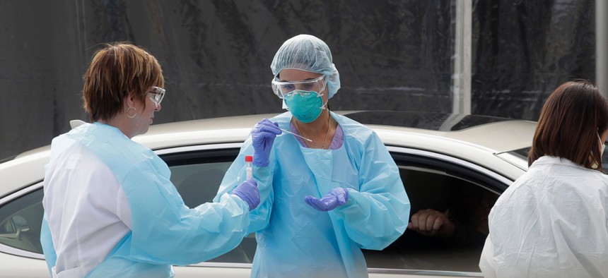 Health care personnel test a person in the passenger seat of a car for coronavirus in San Francisco on March 12.