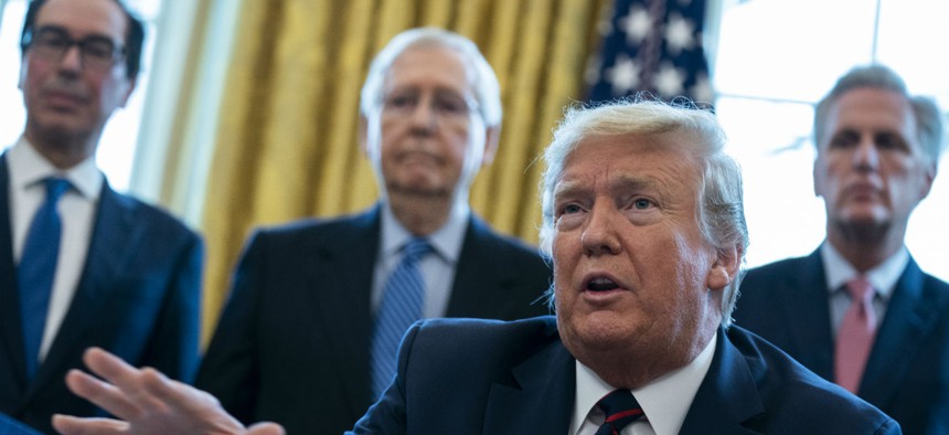 President Trump talks to reporters before signing the coronavirus stimulus relief package in the Oval Office on March 27, as Treasury Secretary Steven Mnuchin, Senate Majority Leader Mitch McConnell and House Minority Leader Kevin McCarty look on. 