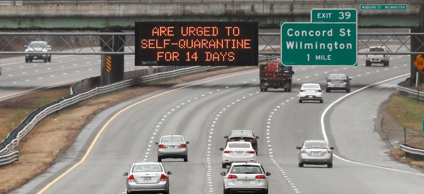 A highway sign urges out of state visitors to self-quarantine for 14 days if they plan on staying in Massachusetts due to the virus outbreak along Route 93 southbound in Wilmington, Mass. on Monday.