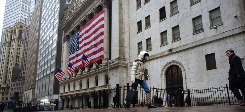 A pedestrian wearing a surgical mask and gloves walks past the New York Stock Exchange in mid-March.  