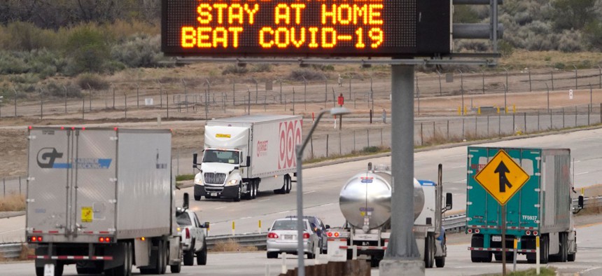 Semi trucks drive by a freeway sign along Interstate 5  in California.