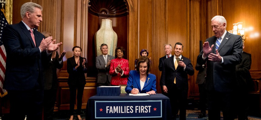 House Speaker Nancy Pelosi of California (center) signs the Coronavirus Aid, Relief and Economic Security Act on March 27.