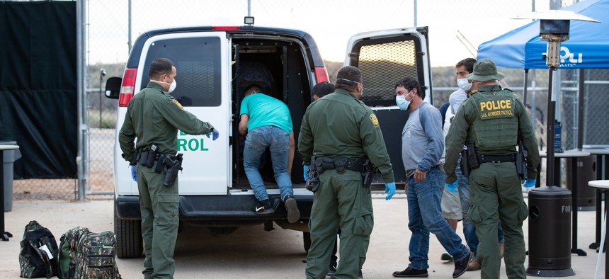 Border Patrol agents use personal protective equipment as they prepare to transport a group of individuals encountered near Sasabe, Ariz. in March.