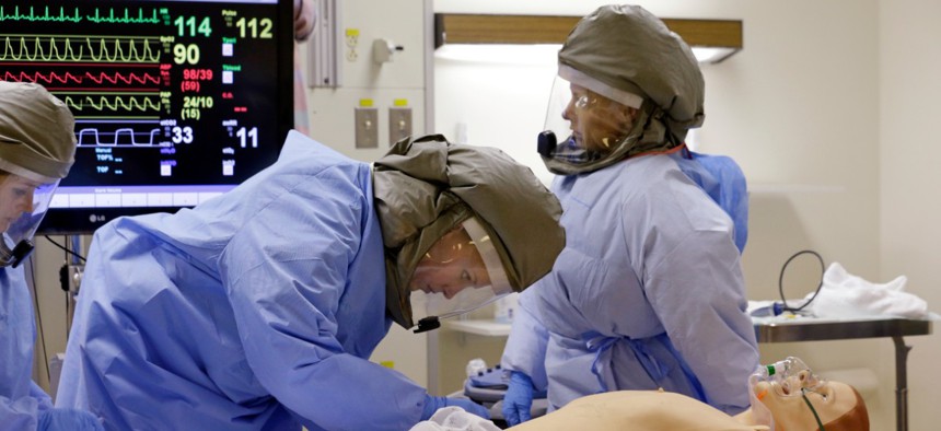 Medical workers wearing PAPR, similar to the ones produced by AirBoss, surround and monitor a simulated patient during a demonstration for media members on their training for working with possible Ebola patients in 2014.