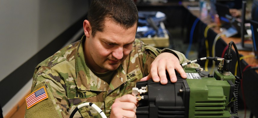 U.S. Army National Guard Pfc. John Veit, JTF 115th Regional Support Group information technology specialist, connects an amplifier for radio communication inside the Joint Operations Center (JOC) Apr. 09, 2020 at the Roseville Armory, Calif