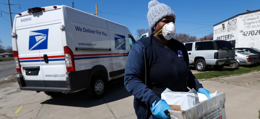 A United States Postal worker makes a delivery with gloves and a mask in Warren, Mich., on April 2.