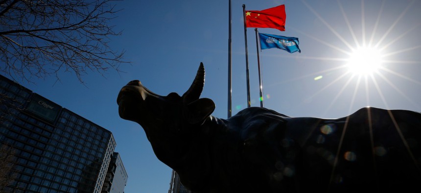 A delivery worker rides his cart by the investment icon bull statue on display outside a bank in Beijing in March. 