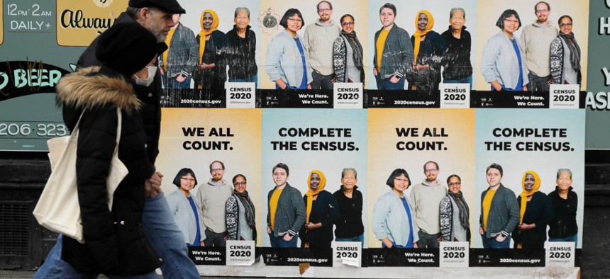 People walk past posters encouraging participation in the 2020 Census in Seattle's Capitol Hill neighborhood in early April.