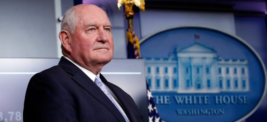 Agriculture Secretary Sonny Perdue listens as President Trump speaks about the coronavirus on April 17. A union representative said USDA leaders do not appear to understand the reality of working from home with children. 