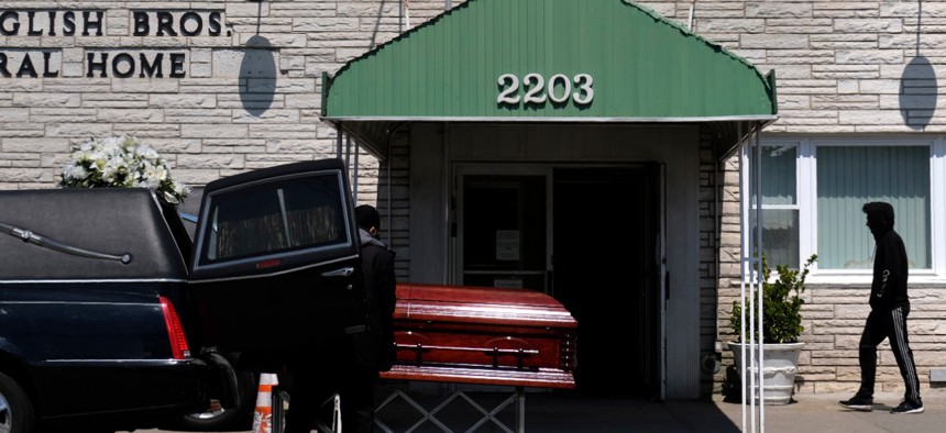 A pedestrian walks past the English Bros Funeral Home as a casket is unloaded in Brooklyn on April 19.