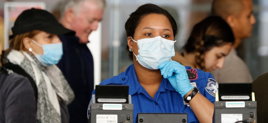 A TSA employee adjusts her face mask while screening passengers entering through a checkpoint at John F. Kennedy International Airport in New York in March. 