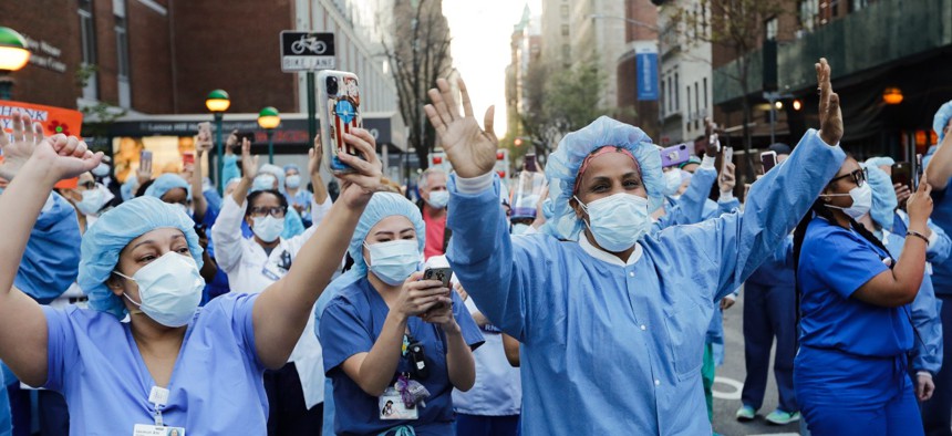 Nurses and medical workers react as police officers and pedestrians cheer them outside Lenox Hill Hospital Wednesday, April 15, 2020, in New York. 