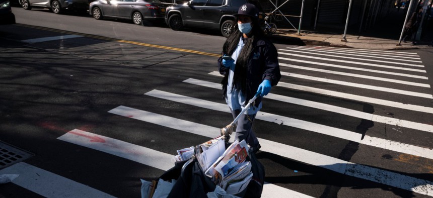 A postal worker wears a mask and gloves as she delivers the mail in Brooklyn in March