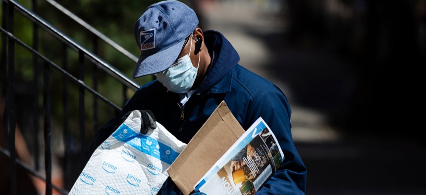 A U.S. Postal Service worker makes a delivery with gloves and a mask in Philadelphia on April 2. 