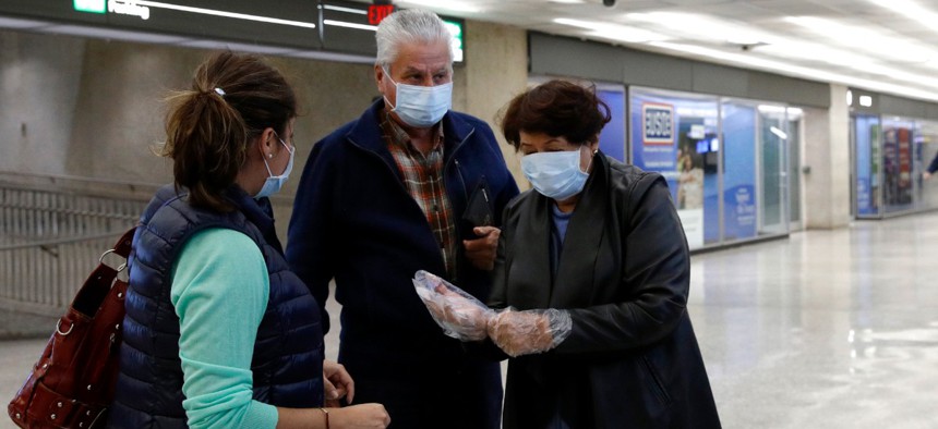 A woman wearing a face mask puts on plastic gloves in an arrivals area at Dulles International Airport in Dulles, Va., on March 17.