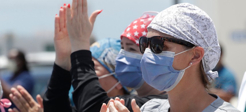 Healthcare workers from Jackson Memorial Hospital clap and cheer as they watch the U.S. Navy's Blue Angels flight demonstration squadron fly by, Friday, May 8, 2020, in Miami. 