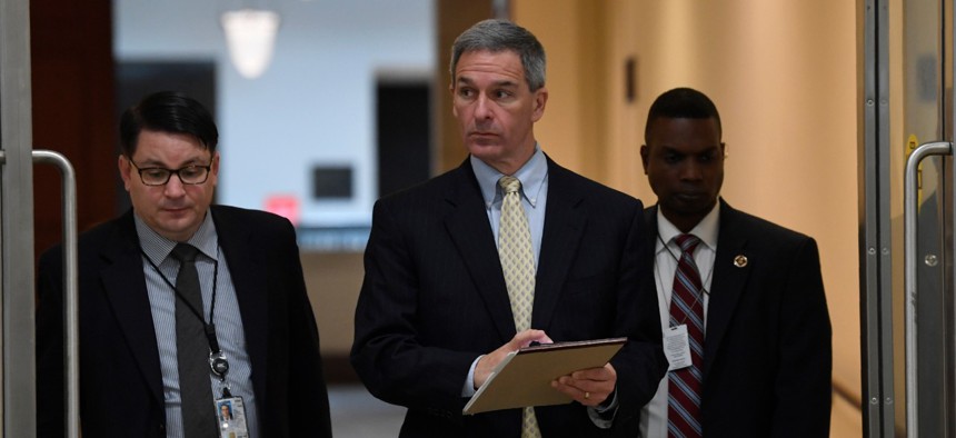 Ken Cuccinelli, center, acting director for the U.S. Citizenship and Immigration Services at the Homeland Security Department, walks on Capitol Hill on March 12 in between briefings on the coronavirus.