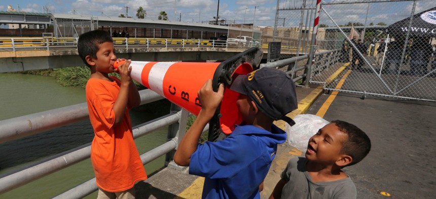 Migrant children play with Customs Border Protection traffic cone, after camping out on the Gateway International Bridge in October.