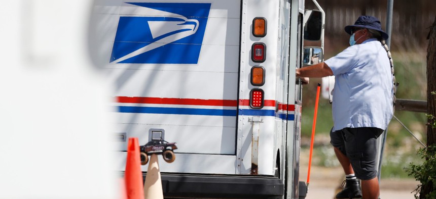 An instructor wears a face mask while directing a new hire on how to drive a delivery van at the U.S. Postal Service distribution facility, Friday, May 22, 2020, in east Denver. 