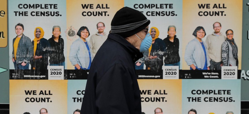 A man walks past posters encouraging participation in the 2020 census on April 1 in Seattle.