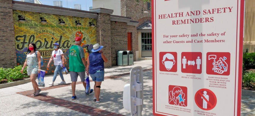 Signs remind patrons to wear masks and other protocols because of the coronavirus pandemic as they stroll through the Disney Springs shopping, dining and entertainment complex on June 16.