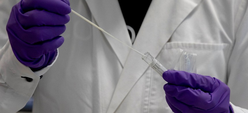 A lab technician inserts a nasal swab into a test tube during research on coronavirus, COVID-19, at Johnson & Johnson subsidiary Janssen Pharmaceutical in Beerse, Belgium