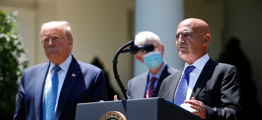 President Donald Trump, left, listens as Moncef Slaoui, a former GlaxoSmithKline executive, speaks about the coronavirus vaccine effort in the Rose Garden of the White House on May 15. 