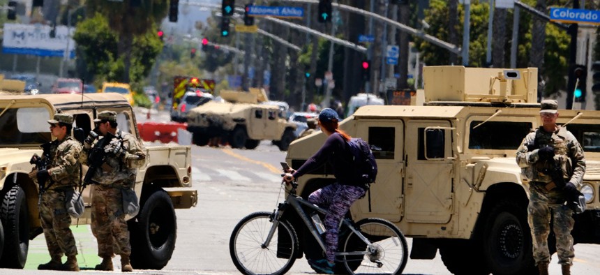 A cyclist rides past a road block with National Guard troops along Ocean boulevard in Santa Monica, Calif. on Sunday June 7.