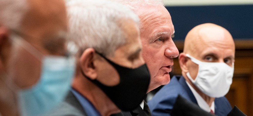 U.S. Public Health Service’s Adm. Brett P. Giroir (unmasked) testifies alongside CDC Director Dr. Robert Redfield, left, NIAID Director Dr. Anthony Fauci and FDA Commissioner Dr. Stephen M. Hahn, right, during a hearing Tuesday.