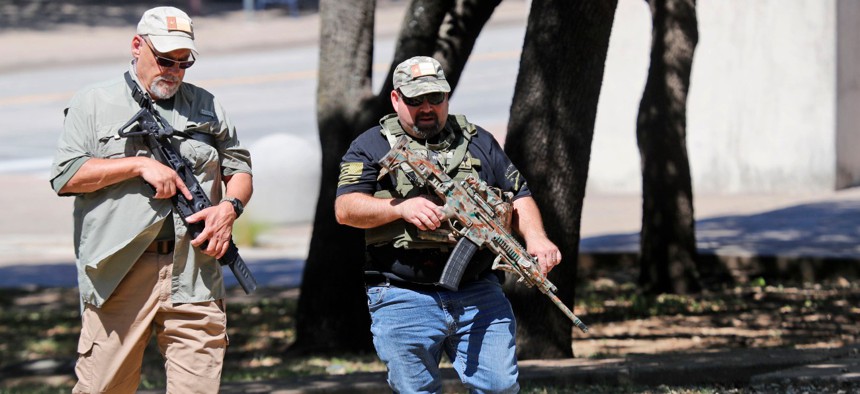 Unidentified armed men walk through Pioneer Park while heading to the Confederate War Memorial in downtown Dallas on June 13. 