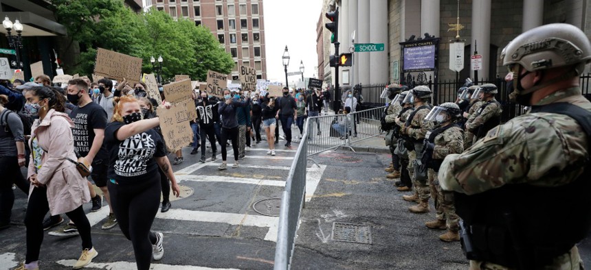 People carry placards, left, as they march past soldiers from the Massachusetts National Guard, right, during a protest against police brutality on June 7.
