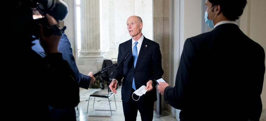 Sen. Rick Scott, R-Fla., center, speaks to a reporter before the Senate Homeland Security and Governmental Affairs committee meets on Capitol Hill on May 20.