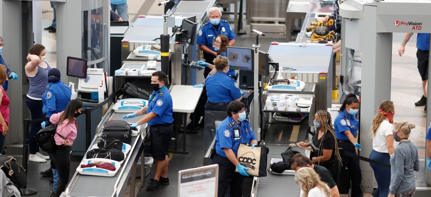 TSA agents work at the south security checkpoint in Denver International Airport in June. TSA has reported a total of 1,171 employees testing positive for COVID-19. 