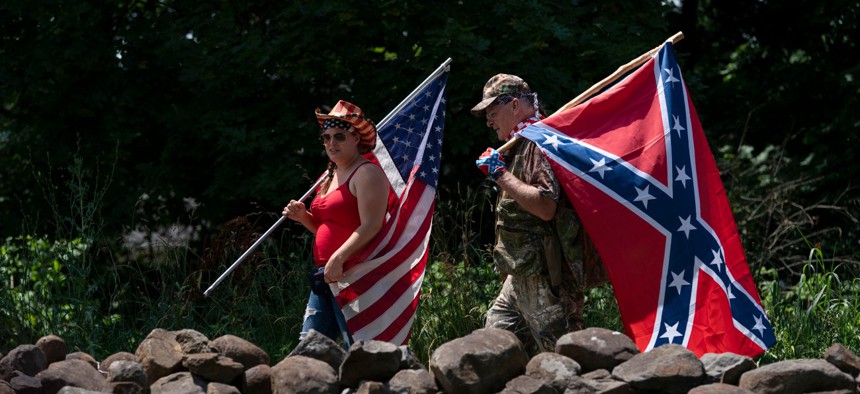 Tourists carry an American flag and a Confederate flag as they walk on a pathway at the Gettysburg National Military Park on July 4. 