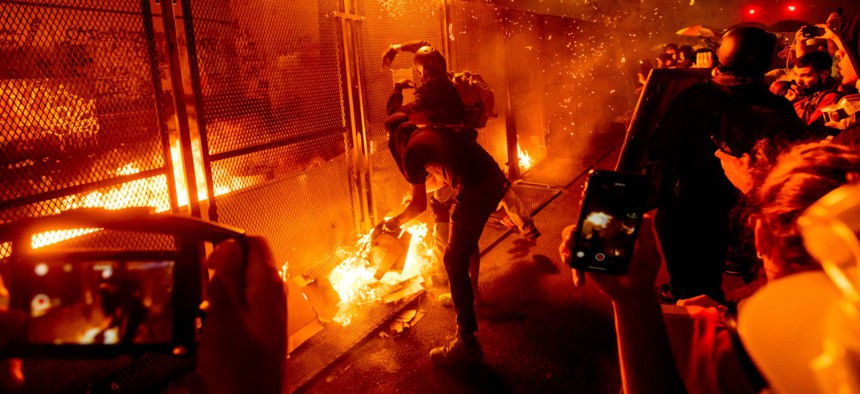 Protesters throw flaming debris over a fence at the Mark O. Hatfield United States Courthouse on July 22 in Portland, Ore. Following a larger Black Lives Matter Rally, several hundred demonstrators faced off against federal officers at the courthouse.