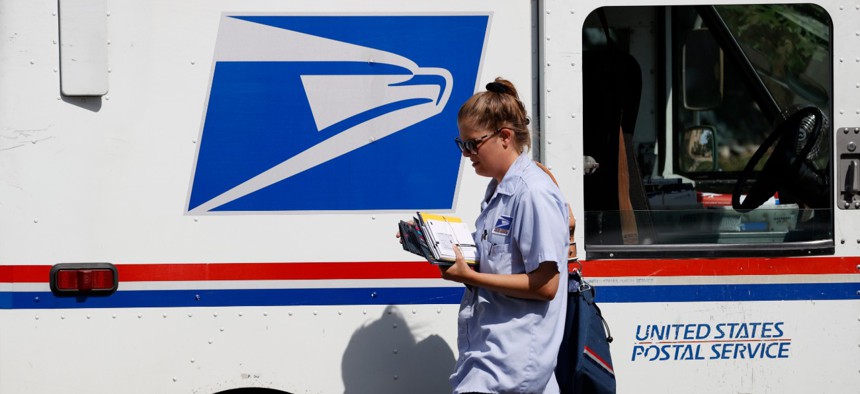 A Postal Service delivery person goes out on her rounds on July 22, 2020, in Denver.