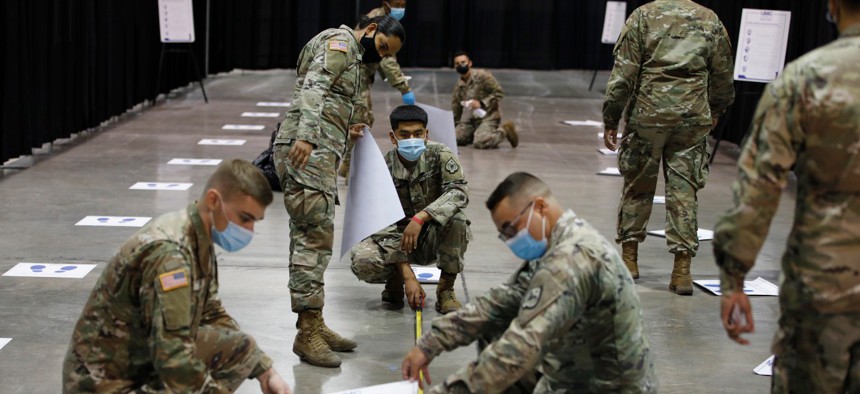 Members of the Nevada National Guard install social distancing stickers while setting up a new temporary coronavirus testing site on Aug. 3 in Las Vegas. 