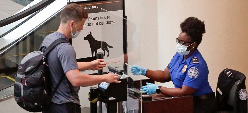 A TSA worker checks a passenger before entering a security screening at Orlando International Airport on June 17. 