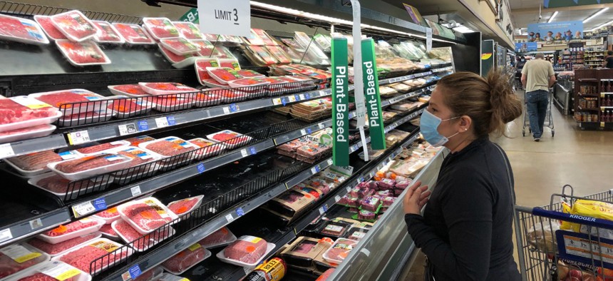 A shopper looks beef at a Kroger store in Atlanta underneath a sign limiting shoppers to three packages of ground beef on Tuesday, May 5, 2020. 