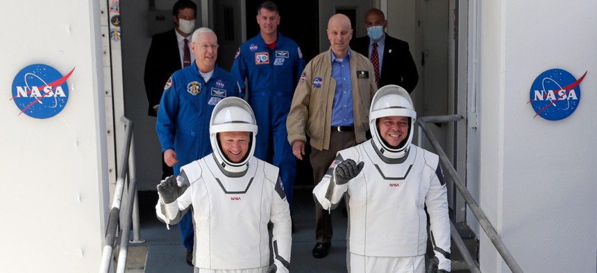 NASA astronauts Douglas Hurley, left, and Robert Behnken walk out of the Neil A. Armstrong Operations and Checkout Building on their way to Pad 39-A at the Kennedy Space Center in Cape Canaveral, Fla., on May 30.